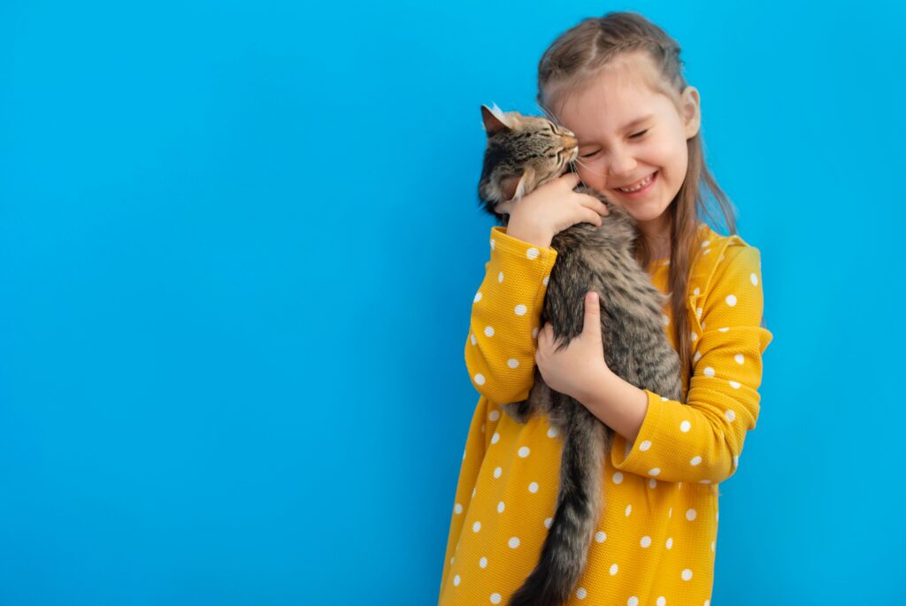 Criança sorrindo e abraçando seu gato